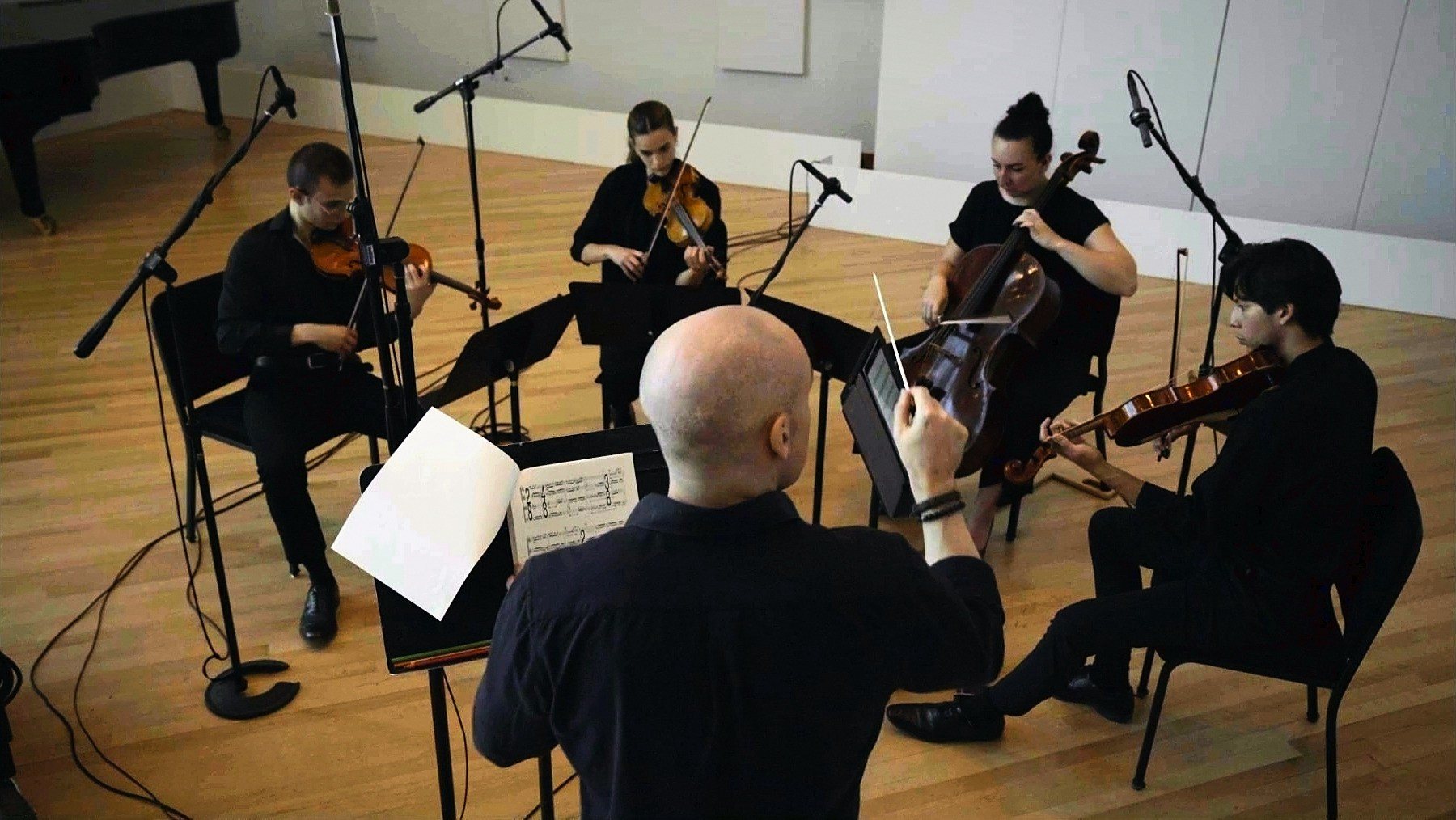 Thomas Vieira conducting a string quartet at a recording session, seen from behind the podium